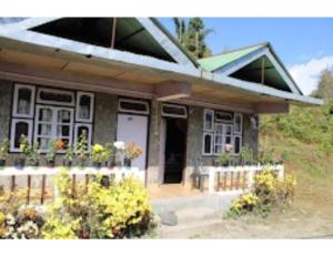 une petite maison avec une terrasse couverte et des fleurs devant elle dans l'établissement Hill Home Stay, Mankhim Road, Aritar, Sikkim, à Aritar