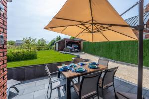 a wooden table with chairs and an umbrella on a patio at unique hideaway, holiday house with large garden in Kortenaken