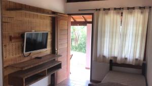 a living room with a tv on a wall at Chalés do Recanto in São João del Rei