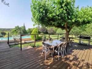 un tavolo e sedie su una terrazza in legno con un albero di Gîte la Saume a Lambesc