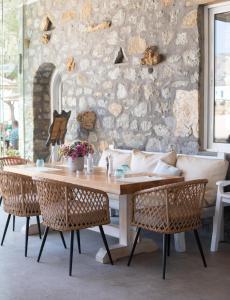 - une table et des chaises dans une pièce dotée d'un mur en pierre dans l'établissement Agrari Ninemia Mykonos, à Agrari