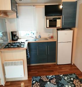 a small kitchen with green cabinets and a white refrigerator at Mobil home 5 pers proche d'Europa Park E020 in Boofzheim