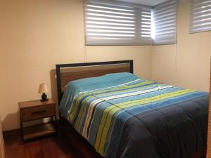 a bed in a bedroom with two windows and a nightstand at Apartamento acogedor en Achumani in La Paz