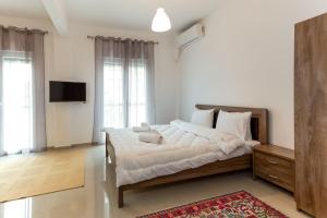 a bedroom with a bed with white sheets and a television at Elegant Apartment in Thessaloniki