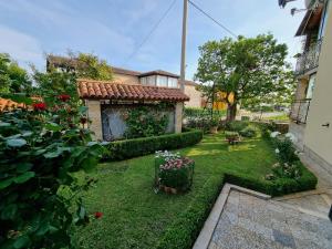 een achtertuin met een tuin met bloemen en een huis bij Apartment Felice in Novigrad Istria