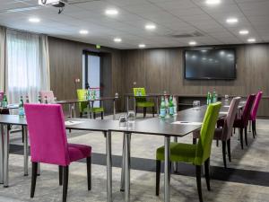 a conference room with tables and chairs and a screen at B&B HOTEL Strasbourg Nord Schiltigheim Lac 4 étoiles in Schiltigheim