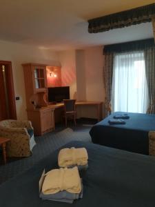 a hotel room with two beds and a desk at Hotel Isolabella Wellness in Fiera di Primiero