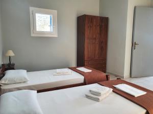 Habitación con 2 camas y ventana en Galini Rooms Sikinos Travel en Síkinos