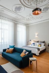 ein Schlafzimmer mit einem blauen Sofa und einem Bett in der Unterkunft Baumhaus Serviced Living - Art & Design Apartments in Porto