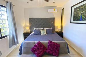 een slaapkamer met een bed met paarse kussens erop bij Beachside Oasis ! Spacious ½ block from the Beach in Puerto Morelos