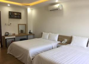 a hotel room with two beds with white sheets at Long Hồ Homestay in Xóm Mỹ Ca