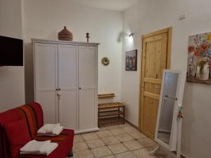 uma sala de estar com um armário branco e um sofá vermelho em La Dimora di Helios em Noto