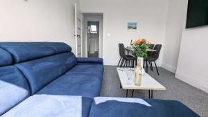 a blue couch in a living room with a table at Sandy Beach Apartment by Seaside Llandudno in Llandudno