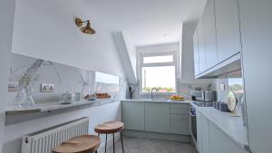 a white kitchen with two stools and a sink at Sandy Beach Apartment by Seaside Llandudno in Llandudno