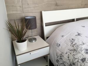 a bed with a nightstand with a lamp and a plant at The Bolthole in Limekilns