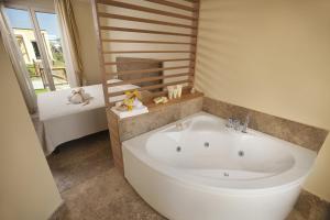 baño con una gran bañera blanca y ventana en Toscana Biovillage - Private Cottage, en Cecina