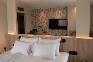 Elle comprend un lit avec des oreillers blancs et une télévision à écran plat. dans l'établissement HOTEL GRACIAN, à Sremska Mitrovica