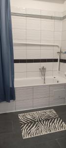 a bathroom with a tub and a zebra rug at Kriston Apartman 2 in Miskolc