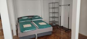 un letto con lenzuola e cuscini verdi in una stanza di Kriston Apartman 2 a Miskolc