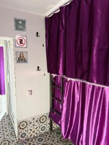 uma cortina roxa num quarto com um espelho em Sunny Hostel - Günəşli Hostel em Baku