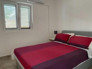 Villa Miran Boka Bay في كراشيسي: غرفة نوم بسرير كبير وملاءات حمراء وأرجوانية