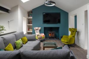 a living room with a couch and a blue wall at Ty Uchaf Cottage in Llansantffraid Glan Conwy