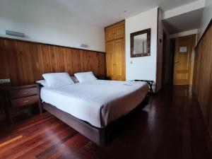 a bedroom with a large white bed with wood paneling at Hotel Rural Cuartamenteru in Llanes