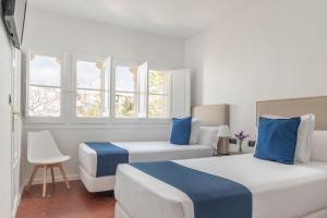 two beds in a room with two windows at Hotel Medium Sitges 1883 in Sitges