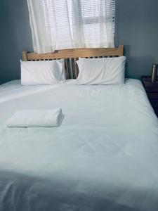 uma grande cama branca com duas almofadas e uma janela em Pule's Home em Maseru