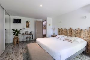 Un dormitorio con una gran cama blanca y una mesa en Chambres d'Hôtes Château Pierre de Montignac, en Civrac-en-Médoc