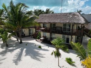 a house on the beach with palm trees in front of it at Grand Slam Fishing Lodge Tulum in Punta Allen