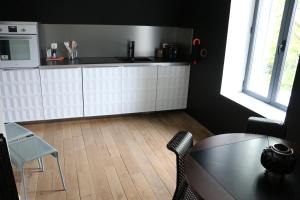 eine Küche mit weißen Schränken sowie einem Tisch und Stühlen in der Unterkunft Maison Valmer - L'armateur, élégant penthouse classé 4 étoiles in Le Havre