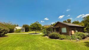 a log cabin in a yard with green grass at נופי הבשן - חדרי אירוח מושלמים לזוגות ומשפחות בלהבות הבשן in Lahavot HaBashan