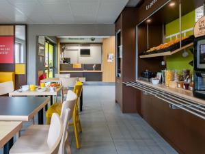 a restaurant with tables and chairs and a counter at B&B HOTEL Strasbourg Nord Artisans in Vendenheim