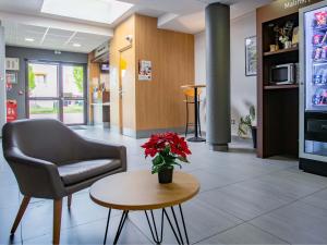 a waiting room with a chair and a table at B&B HOTEL Strasbourg Nord Artisans in Vendenheim