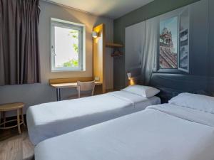 フェンデンハイムにあるB&B HOTEL Strasbourg Nord Artisansのベッド2台、テーブル、窓が備わるホテルルームです。