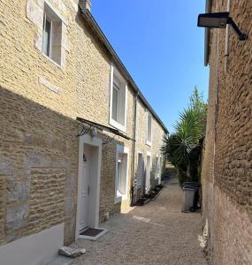 um beco entre dois edifícios de tijolos com uma porta branca em Maison 2 pas du centre ville et proche plage em Courseulles-sur-Mer