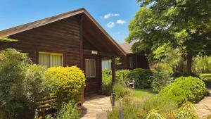 Nofey HaBashan Country Lodging في Lahavot HaBashan: منزل خشبي وامامه حديقة