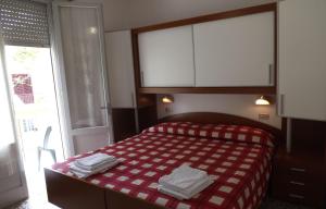 a bedroom with a bed with a red and white blanket at Hotel La Vela in Bellaria-Igea Marina