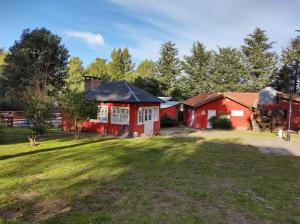 a red house with a black roof in a yard at Complejo Las Pinochas in Villa Ventana