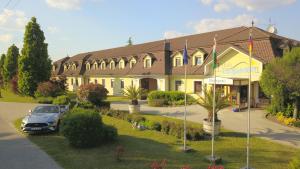 a building with a car parked in front of it at Hétkúti Wellness Hotel in Mór