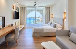 Hotel Blau Parc في سان أنطونيو: غرفة نوم مع سرير وغرفة معيشة مع أريكة
