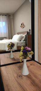 a bedroom with a bed and two vases with flowers on a table at Cruzeto in Syvota