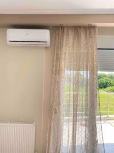 a window with a curtain and a air conditioner at Olymp Family Apartments Katerini in Katerini