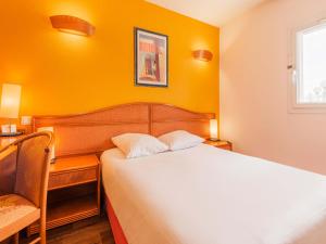 Cette chambre jaune comprend un lit et une chaise. dans l'établissement B&B HOTEL Strasbourg Aéroport, à Holtzheim