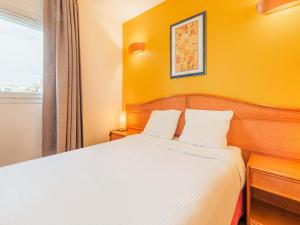 - une chambre avec un lit et un mur jaune dans l'établissement B&B HOTEL Strasbourg Aéroport, à Holtzheim