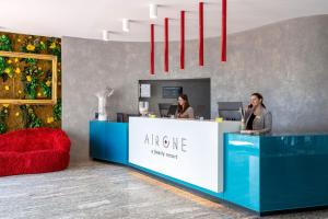 two women are sitting at a counter in a lobby at B&B Hotel Chioggia Airone in Sottomarina