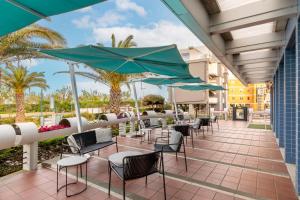 a patio with chairs and umbrellas at the resort at B&B Hotel Chioggia Airone in Sottomarina