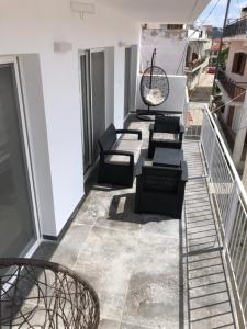 a balcony with chairs and tables on a building at Alex Apartments Skiathos in Skiathos Town