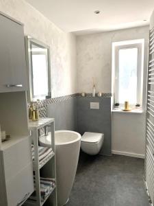 uma casa de banho com uma banheira, um WC e 2 janelas. em Ferienwohnung Appartamento Da Vinci em Eisenach